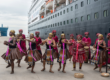 Artistas locales junto a un crucero durante una escala
